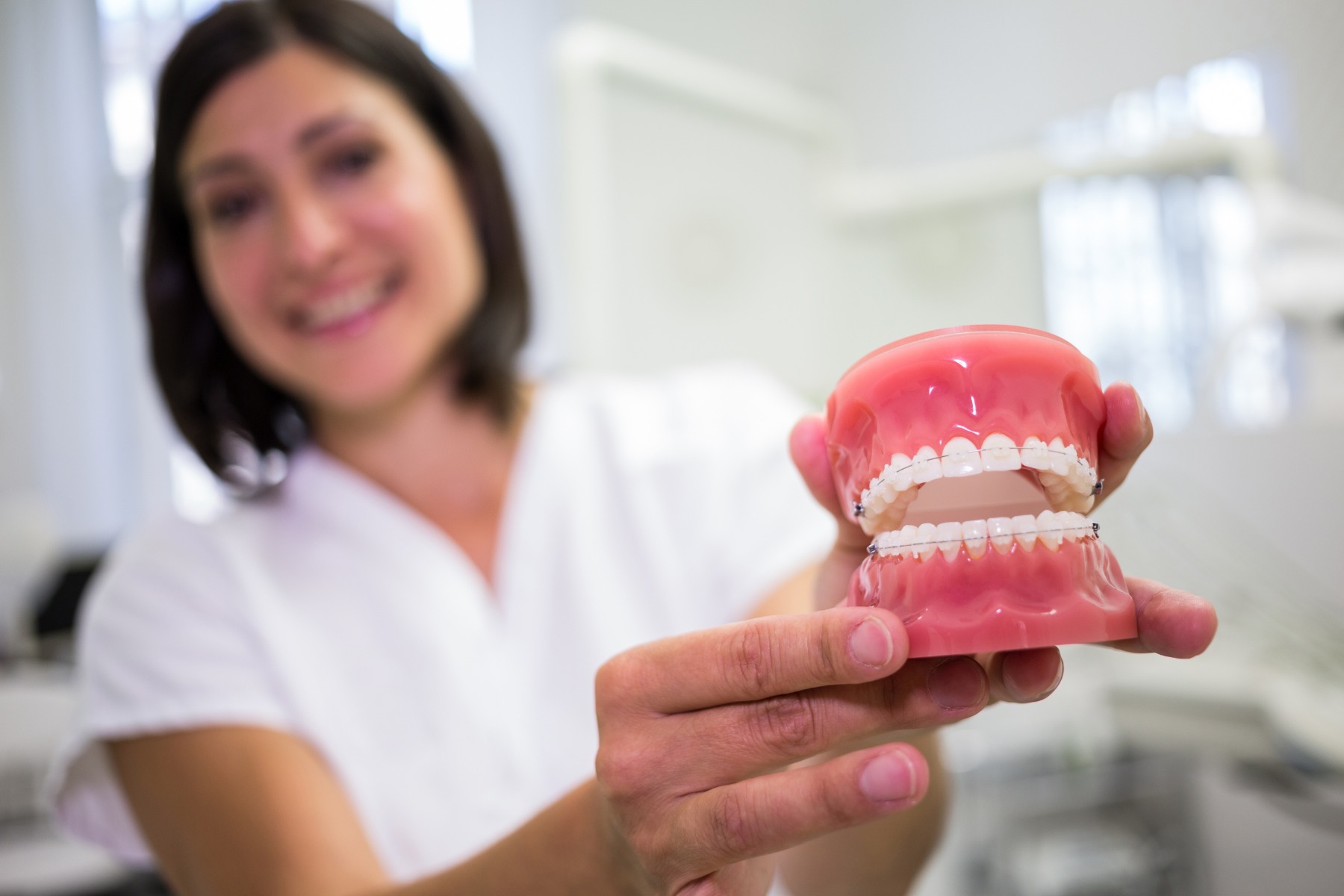 Une dentiste présentant des prothèses dentaires à la caméra.