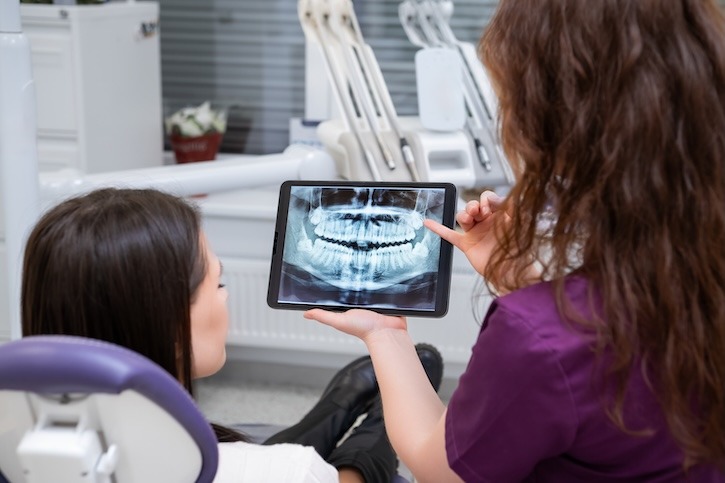 Un dentiste montrant un scanner dentaire à un patient.
